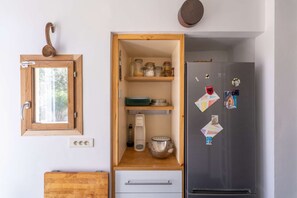 Eine Küche mit einem Holzkasten, einem Edelstahlkühlschrank und einem Fenster mit einem Holzgriff.