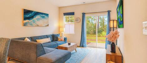 A modern living room with a sofa, coffee table, and a painting on the wall.