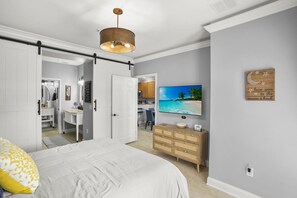 A bedroom with a bed, a dresser, a television, and a door leading to a bathroom. - Waterstone Paradise | Your 5 star Florida Stay (Davenport)