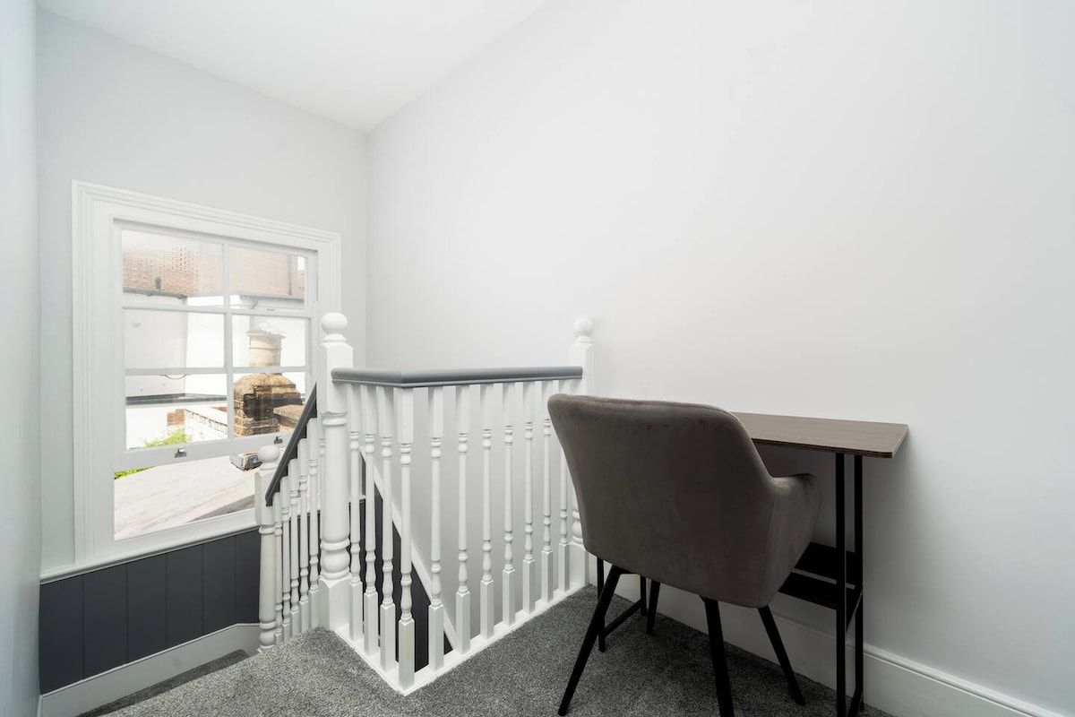 A room with a white railing, a chair, and a window.