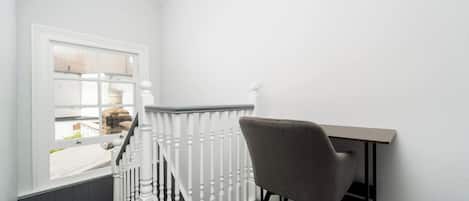 A room with a white railing, a chair, and a window.