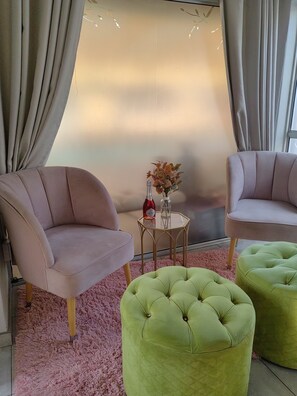 A room with two armchairs, a small table with a vase, and a pink rug.