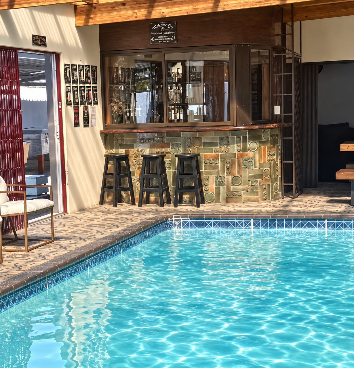 A poolside bar with stools and a sign above it.