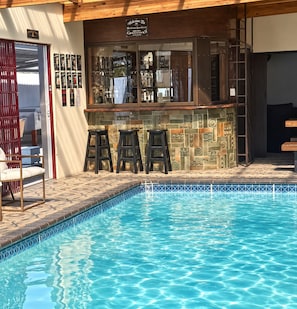 Un bar junto a la piscina con taburetes y un letrero encima.