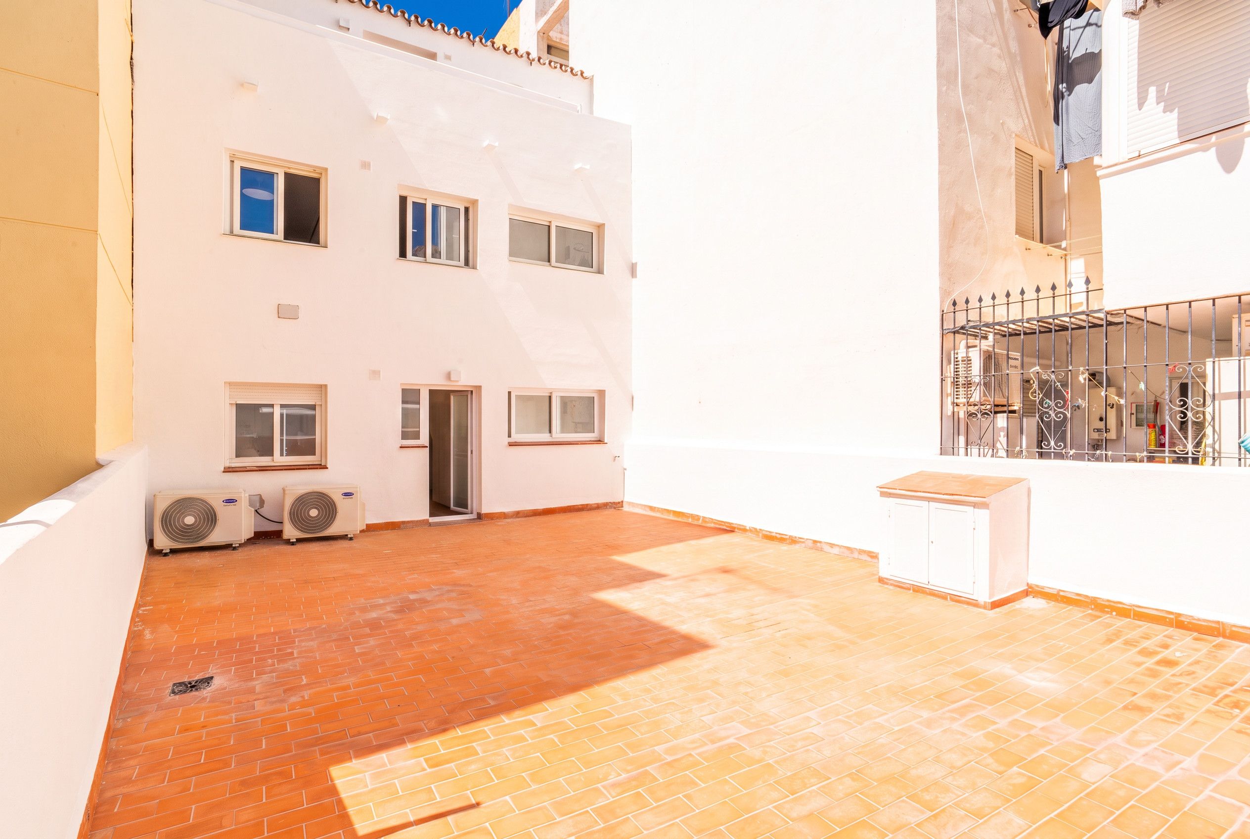 A building with multiple windows, a door, and two air conditioning units on the ground floor.