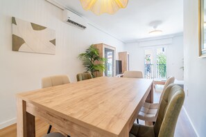 Un espace de repas moderne avec une table et des chaises en bois, une plante en pot et une vue sur l’extérieur.