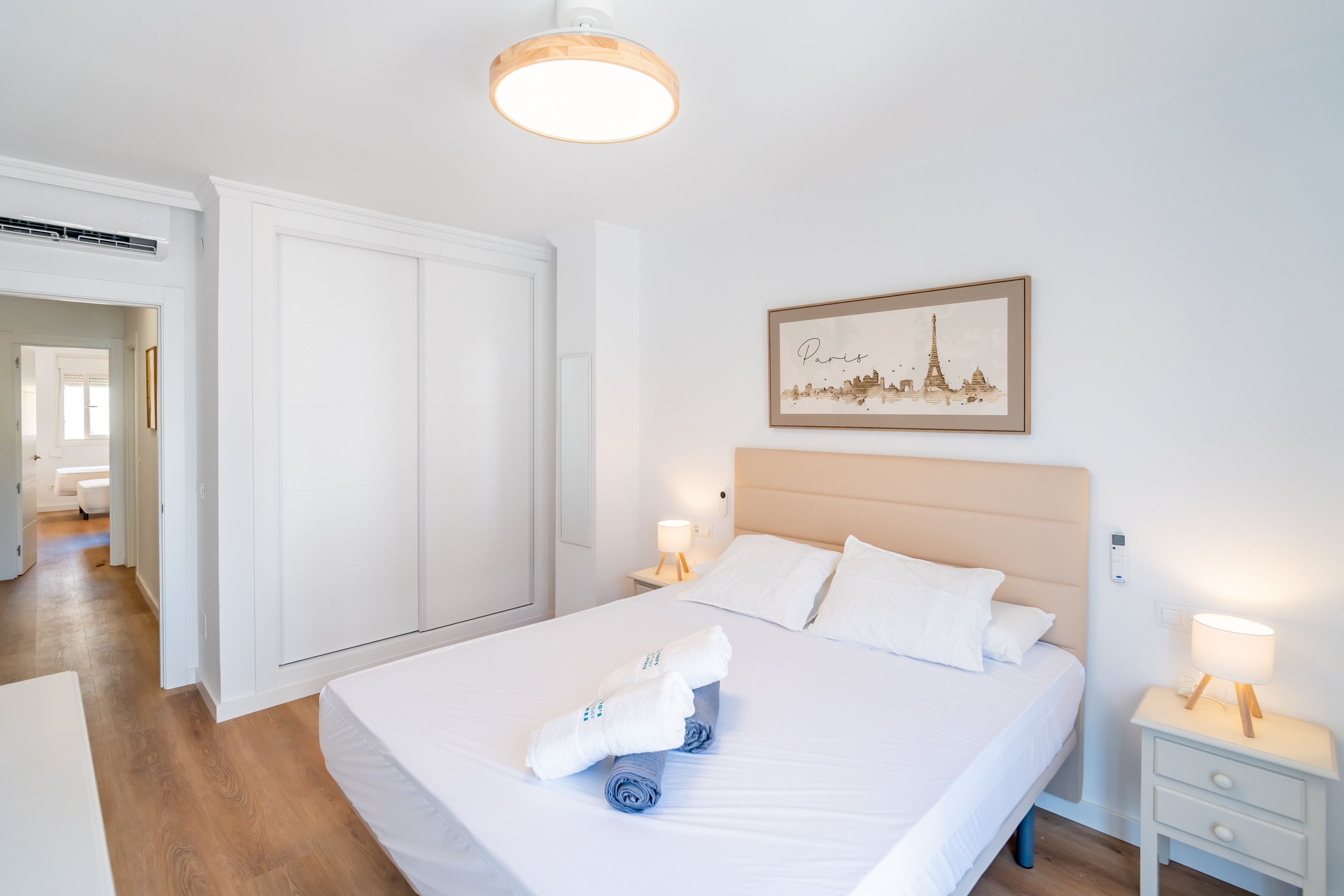 Une chambre d’hôtel avec un lit, une table de chevet, un tableau accroché au mur et une porte.