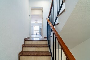 Una escalera con barandilla de madera y balaustradas negras que conduce a una plataforma.