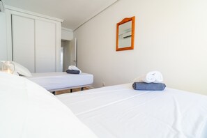 A hotel room with two beds, a wardrobe, a mirror, and a bedside table with a lamp. - Cubo's Suite Sol Fuengirola Apartment / center / air conditioning / free wifi (Fuengirola)