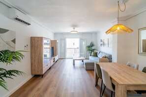 A modern living space with a dining area, a sofa, a TV, and a plant. - Cubo's Suite Sol Fuengirola Apartment / center / air conditioning / free wifi (Fuengirola)