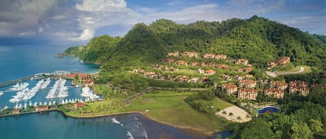 A coastal resort with a marina, beachfront, and hillside villas.