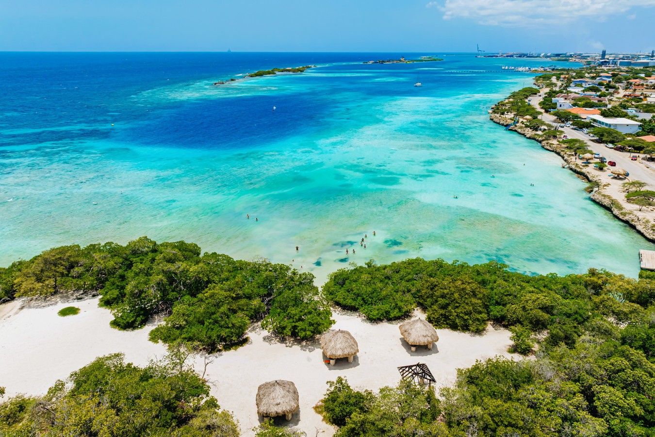 A coastal area with clear turquoise waters, a sandy beach, and lush greenery.