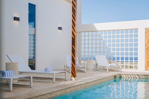 A poolside area with lounge chairs, a pool, and a view of the ocean. - 3BR Sunrise Villa with Ocean Views and Pool near Baby Beach - Casa Cuadra by Bocobay (Noord)