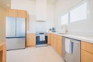 A modern kitchen with stainless steel appliances, wooden cabinets, and a large window providing natural light. - 3BR Sunrise Villa with Ocean Views and Pool near Baby Beach - Casa Cuadra by Bocobay (Noord)