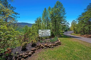 A welcome sign at Deer Ridge with a view of a road and surrounding greenery. - Panoramic Smoky Mountain Views, Indoor Pool, 2 BD (Gatlinburg)