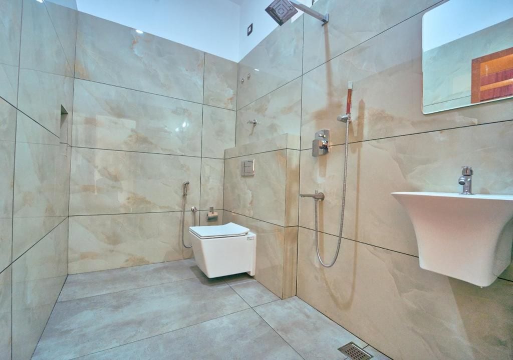 Un baño moderno con ducha a nivel, inodoro y lavamanos.