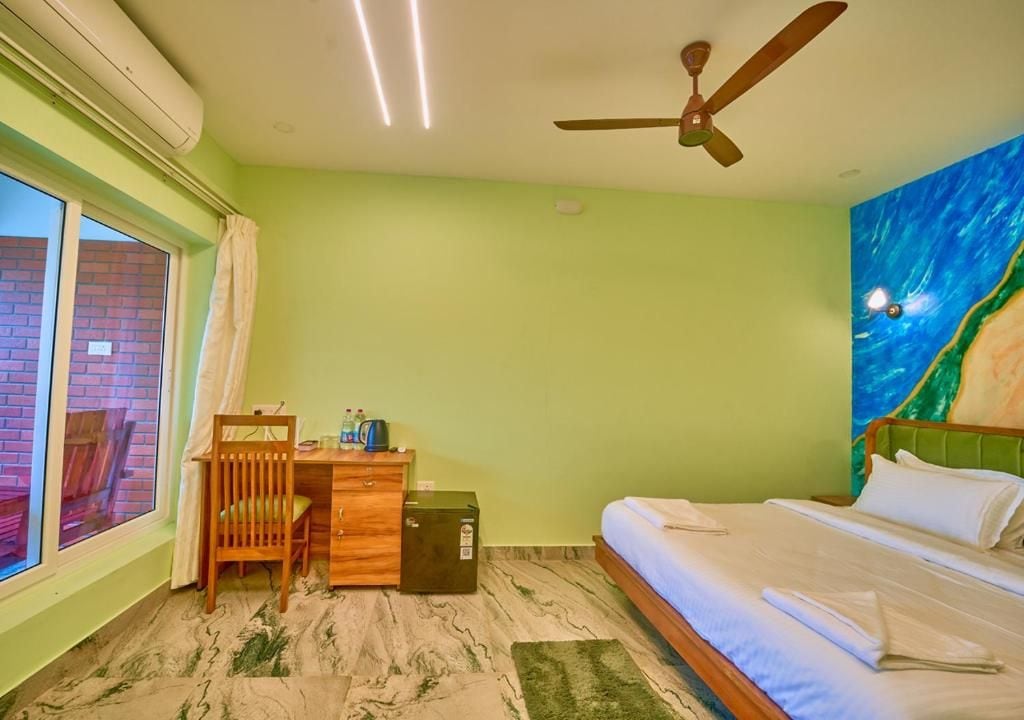 Un dormitorio con cama, escritorio, silla, ventilador de techo y un amplio ventanal.