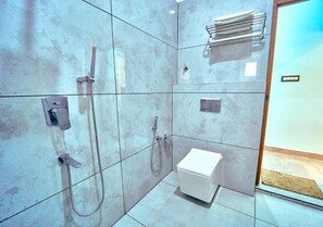 A modern bathroom with a white toilet, a shower with a handheld showerhead, and a towel rack.