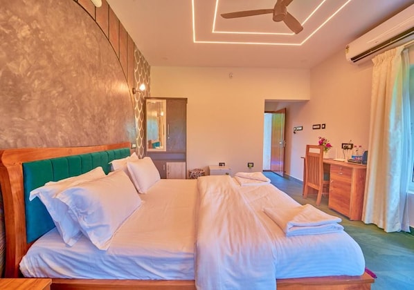 A hotel room with a large bed, a desk, and a chair.