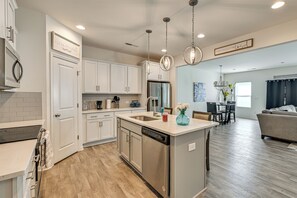 A modern kitchen with white cabinets, stainless steel appliances, and pendant lighting. - New-build Townhome Near Speedway & Uncc (Charlotte)