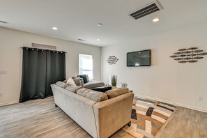 A modern living room with a sofa, a flat-screen TV, decorative wall art, and a patterned rug. - New-build Townhome Near Speedway & Uncc (Charlotte)