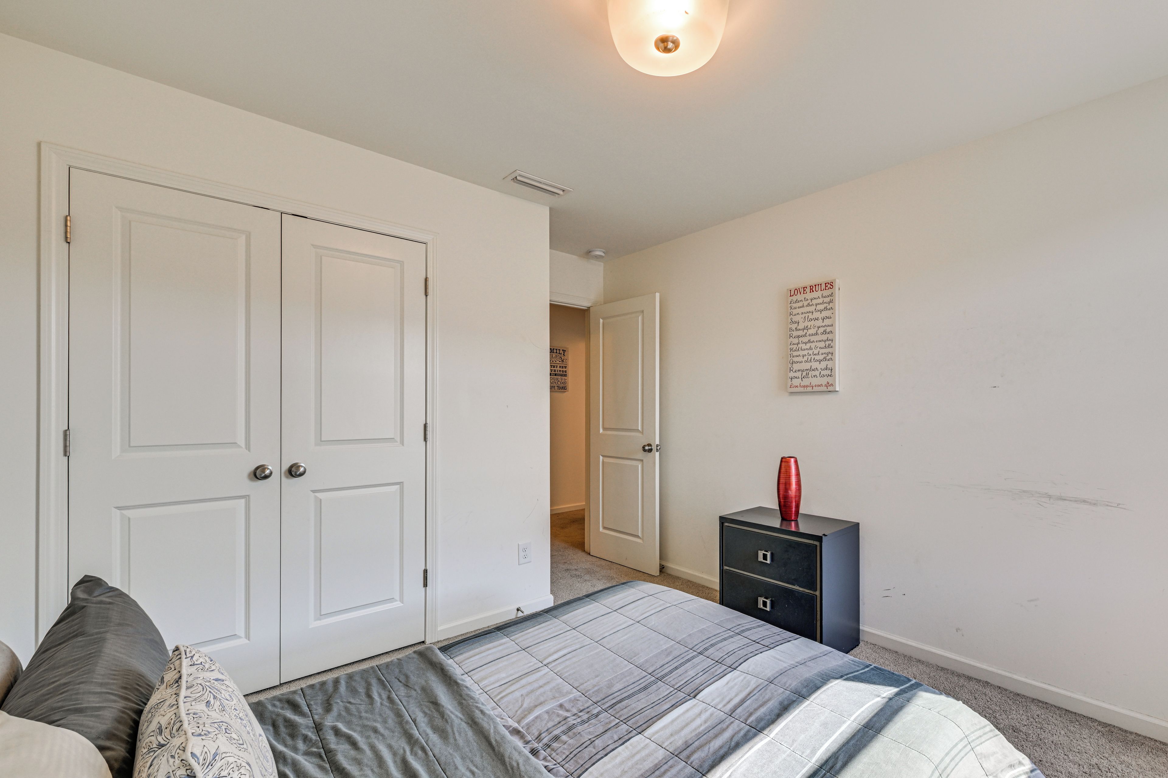 Un dormitorio con cama, cómoda y lámpara de pared.