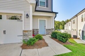 A residential house with a front door, garage, and a stone accent wall. - New-build Townhome Near Speedway & Uncc (Charlotte)