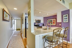 A modern kitchen with white cabinets, stainless steel appliances, and a central island with bar stools. - Steps to Sand! Extended Bradenton Beach Getaway (Bradenton Beach)
