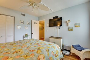 Ein Schlafzimmer mit einem Bett, einem Deckenventilator, einem Fernseher und einem kleinen Tisch mit einem dekorativen Gegenstand.