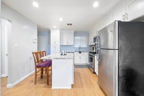 A modern kitchen with white cabinetry, a marble countertop, and a stainless steel refrigerator. - Private Yard & Playset! Sacramento Family Escape (Sacramento)