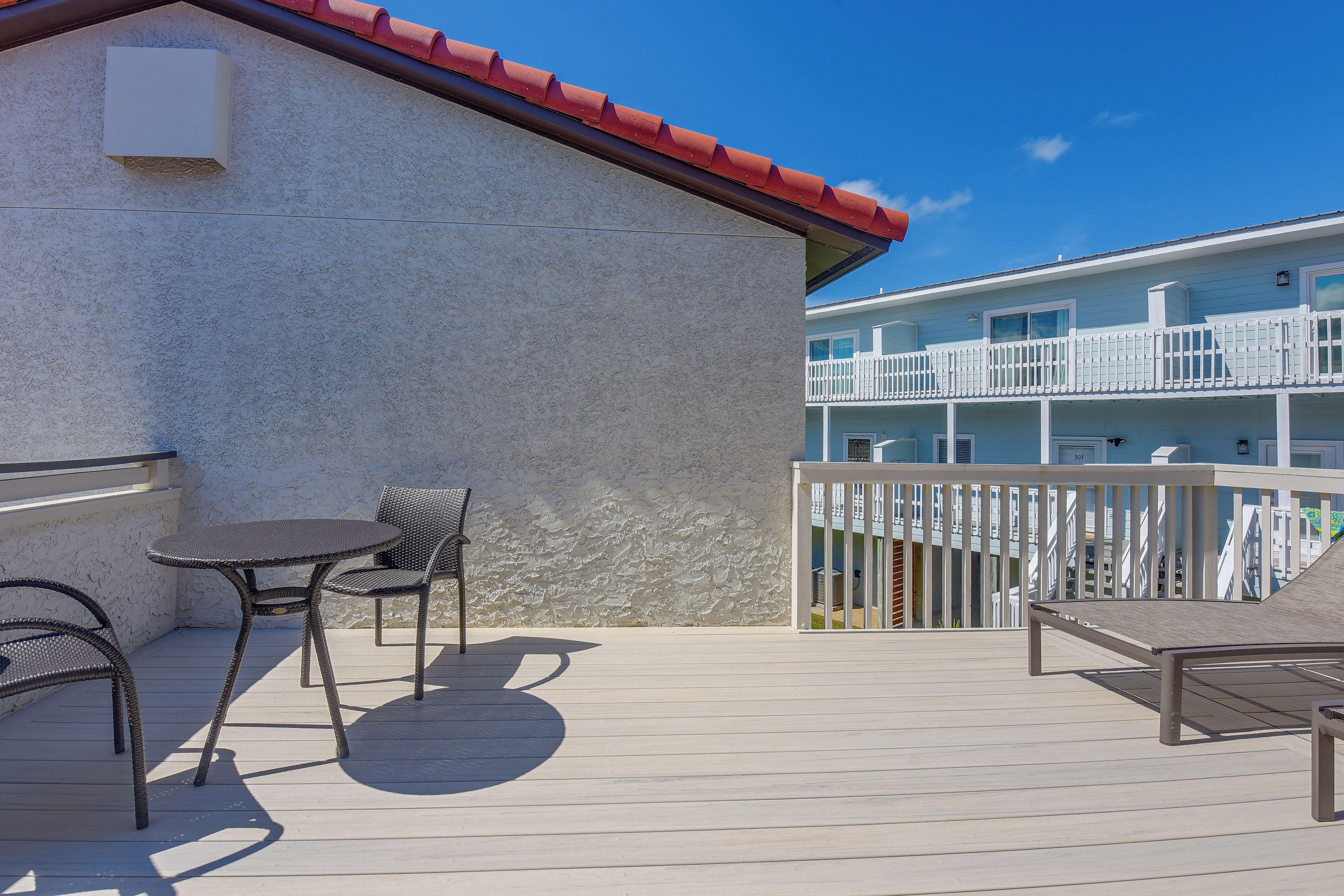 A balcony with wicker furniture and a view of a building with a red roof.
