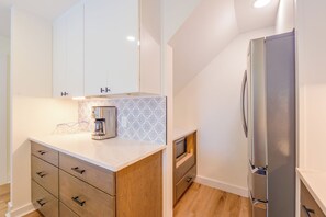 A modern kitchen with white cabinets, a stainless steel refrigerator, and a coffee maker. - Steps to Blue Mountain Beach! 30A Getaway w/ Deck (Santa Rosa Beach)
