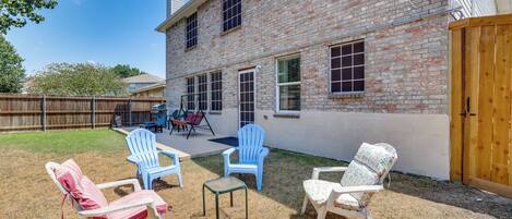 A backyard with a brick house, outdoor seating, and a swing set.