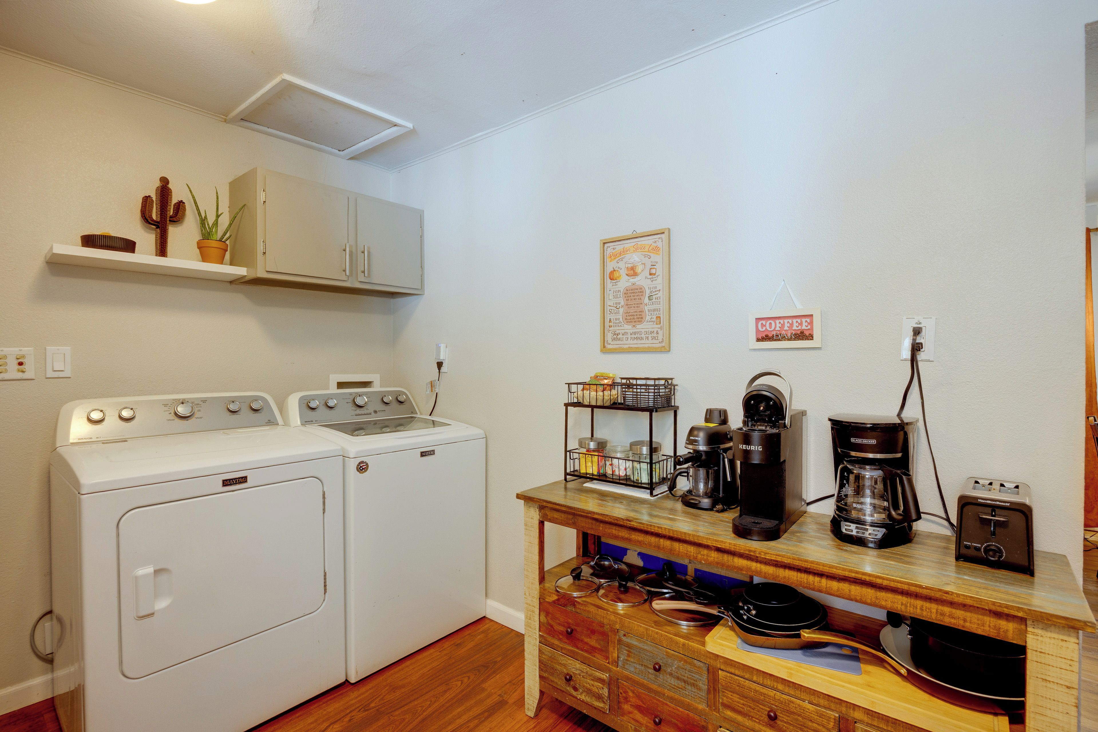 A compact kitchen with a washing machine, a coffee maker, and a toaster.