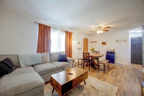 Una sala de estar con sofá, mesa de centro y comedor con sillas.