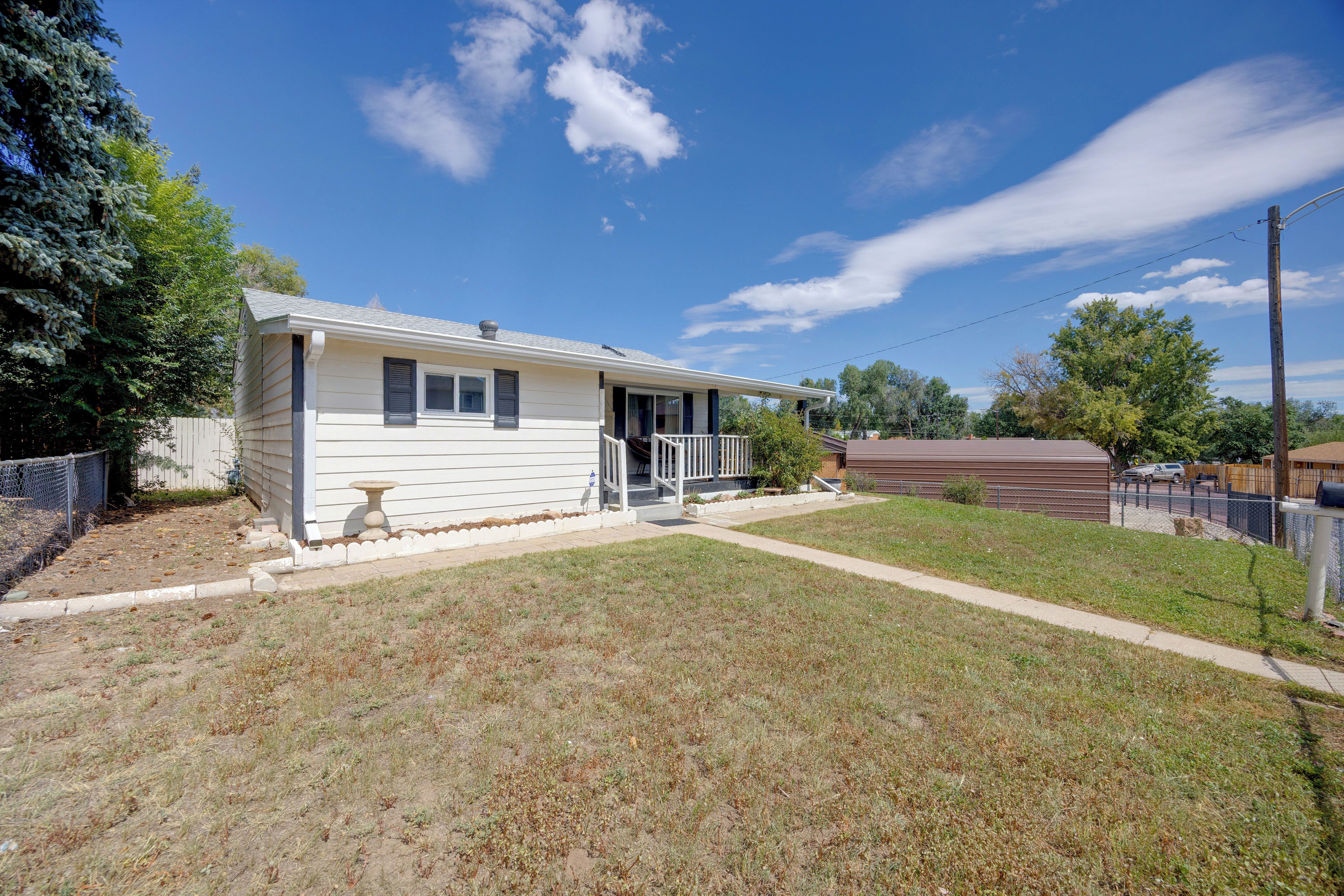 A single-story mobile home with a front porch and a fenced yard.
