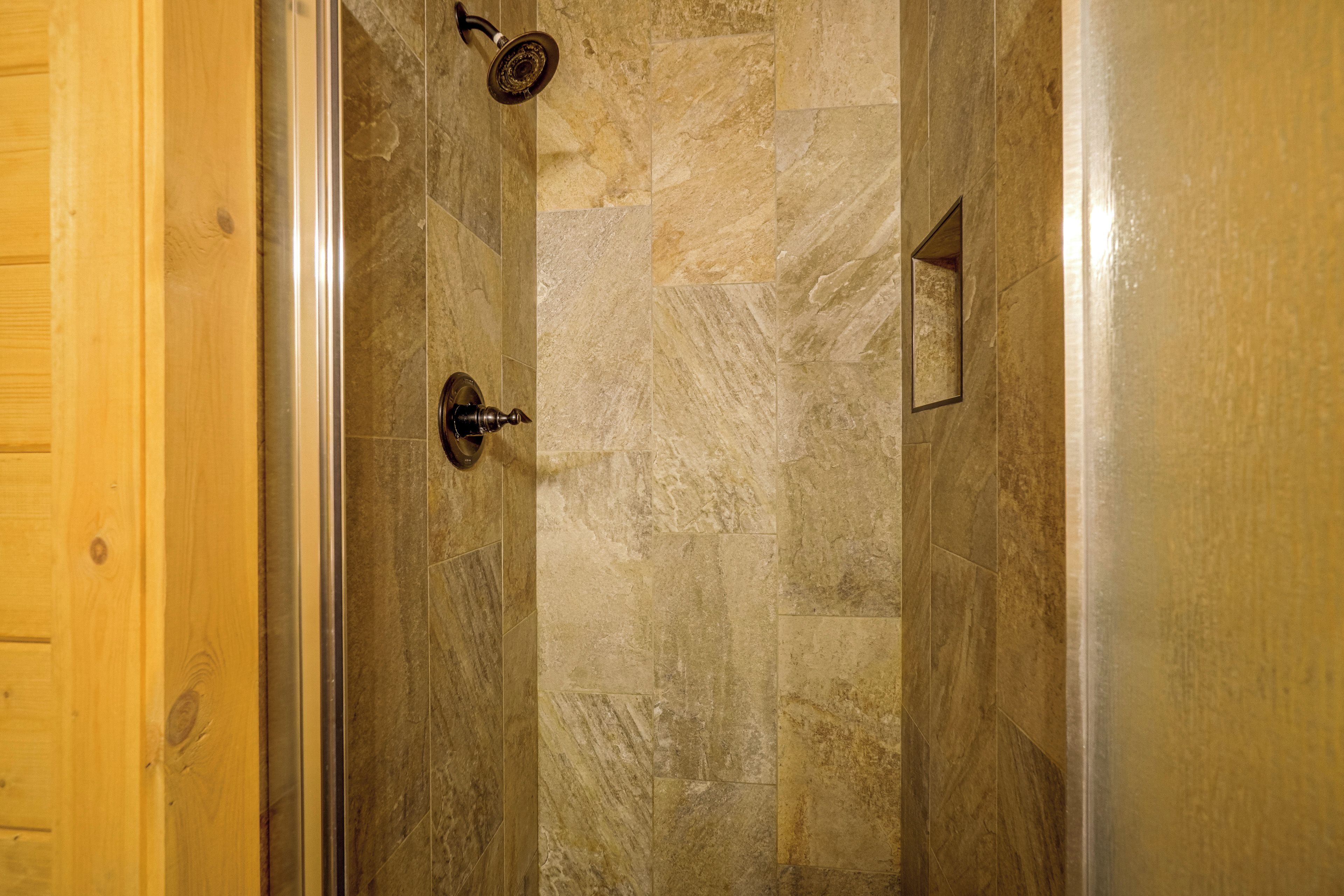 A shower area with stone tiles and a wooden door.