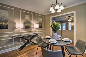 A dining area with a round table, four chairs, a vase with greenery, and wall-mounted lamps. - Walk to Texas Tech! Upscale Family Retreat (Lubbock)