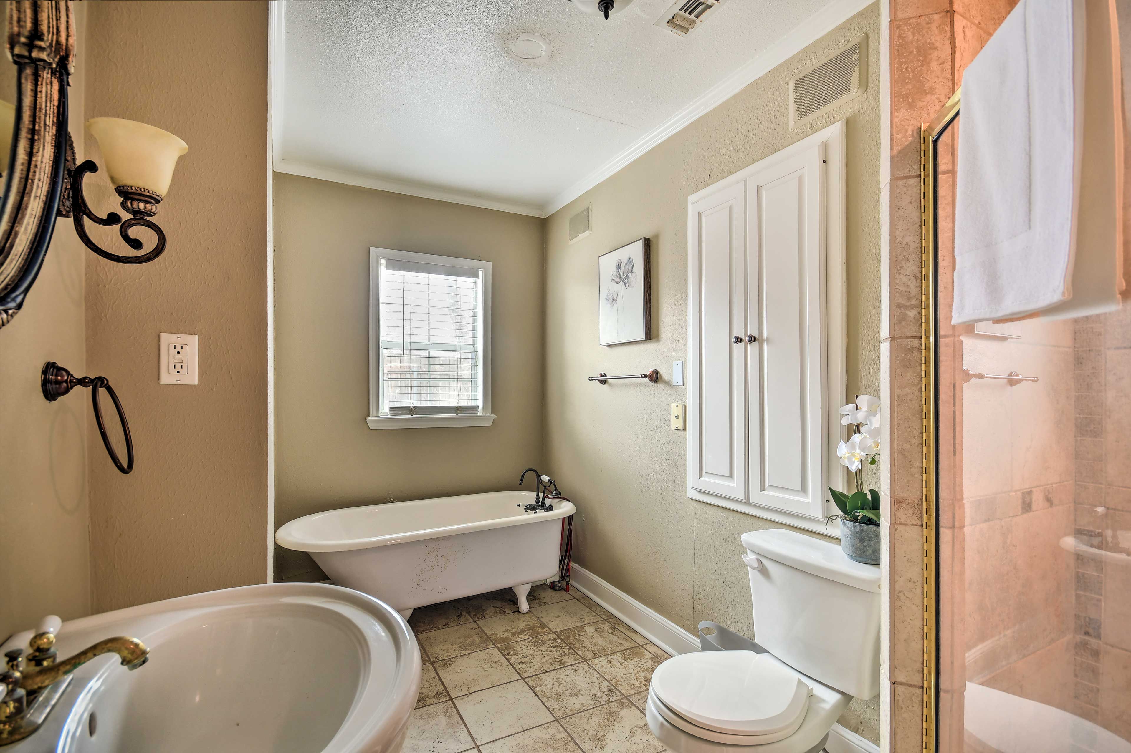 A bathroom with a freestanding bathtub, a toilet, and a shower area.
