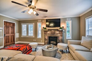 A living room with a fireplace, a ceiling fan, and a large TV mounted on the wall. - Walk to Texas Tech! Upscale Family Retreat (Lubbock)