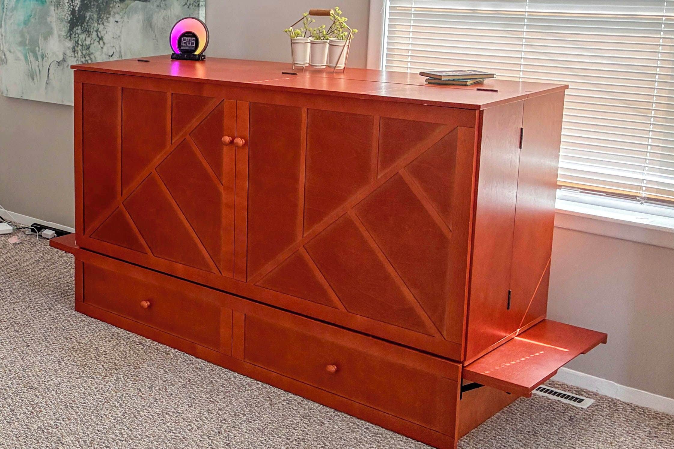 A wooden dresser with drawers and a shelf, placed in a room with a window and a plant.