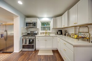 A modern kitchen with white cabinets, stainless steel appliances, and a wooden floor. - Extended Stay Near Yale: East Haven Home w/ Yard! (New Haven)