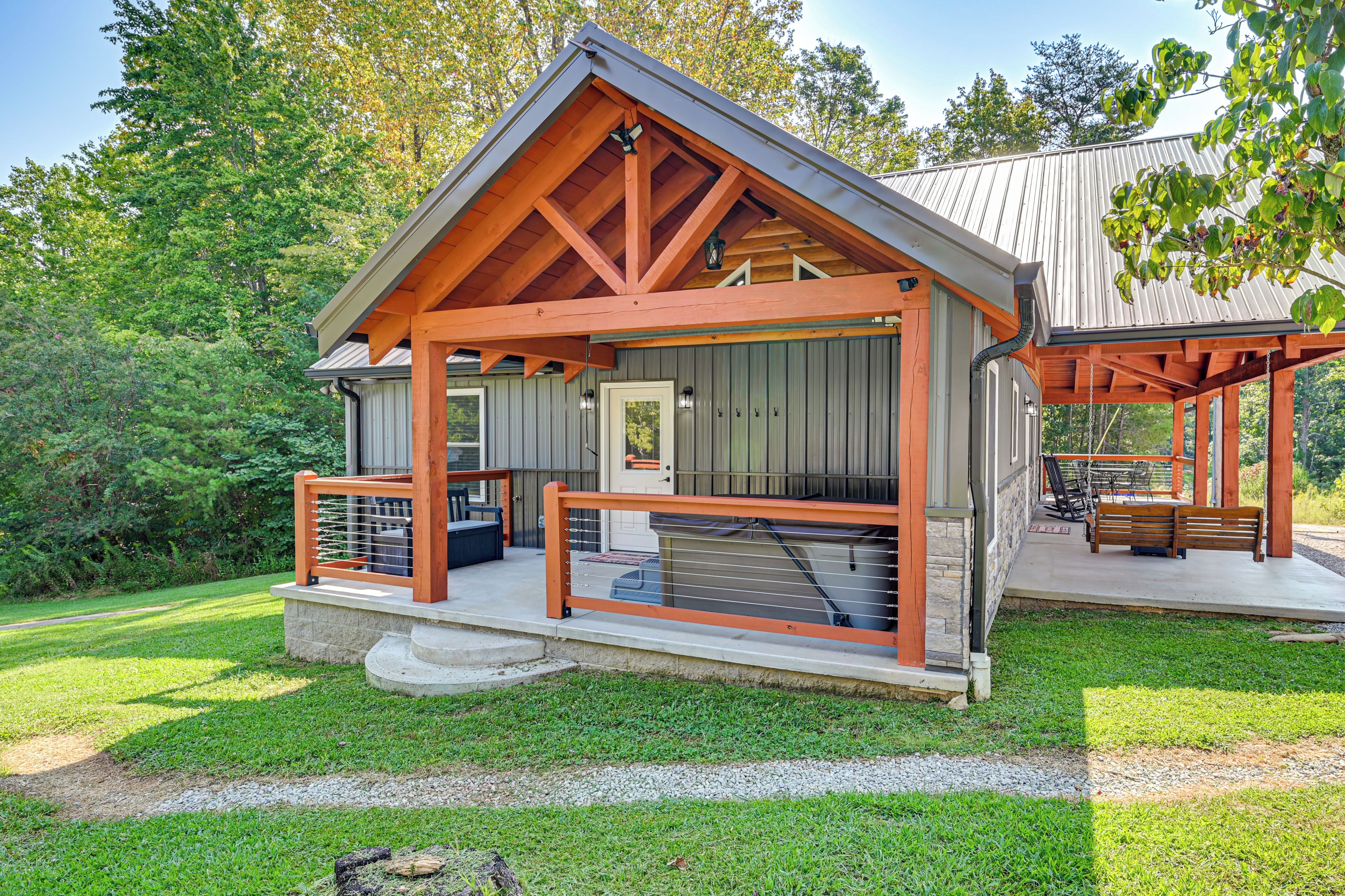 A cabin with a porch, a covered outdoor seating area, and a stone pathway leading to the entrance.
