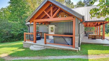 A cabin with a porch, a covered outdoor seating area, and a stone pathway leading to the entrance.
