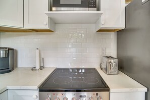 Cozinha com fogão de aço inoxidável, micro-ondas e torradeira.
