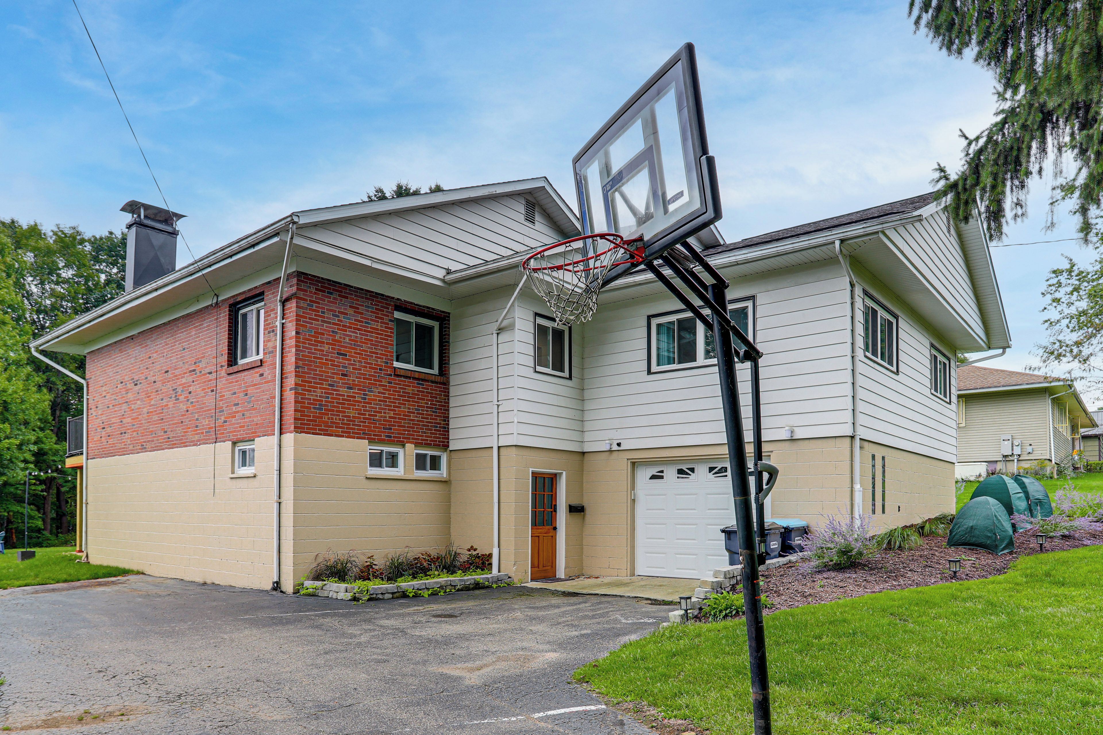 A two-story residential building with a garage, a basketball hoop, and a well-maintained lawn.