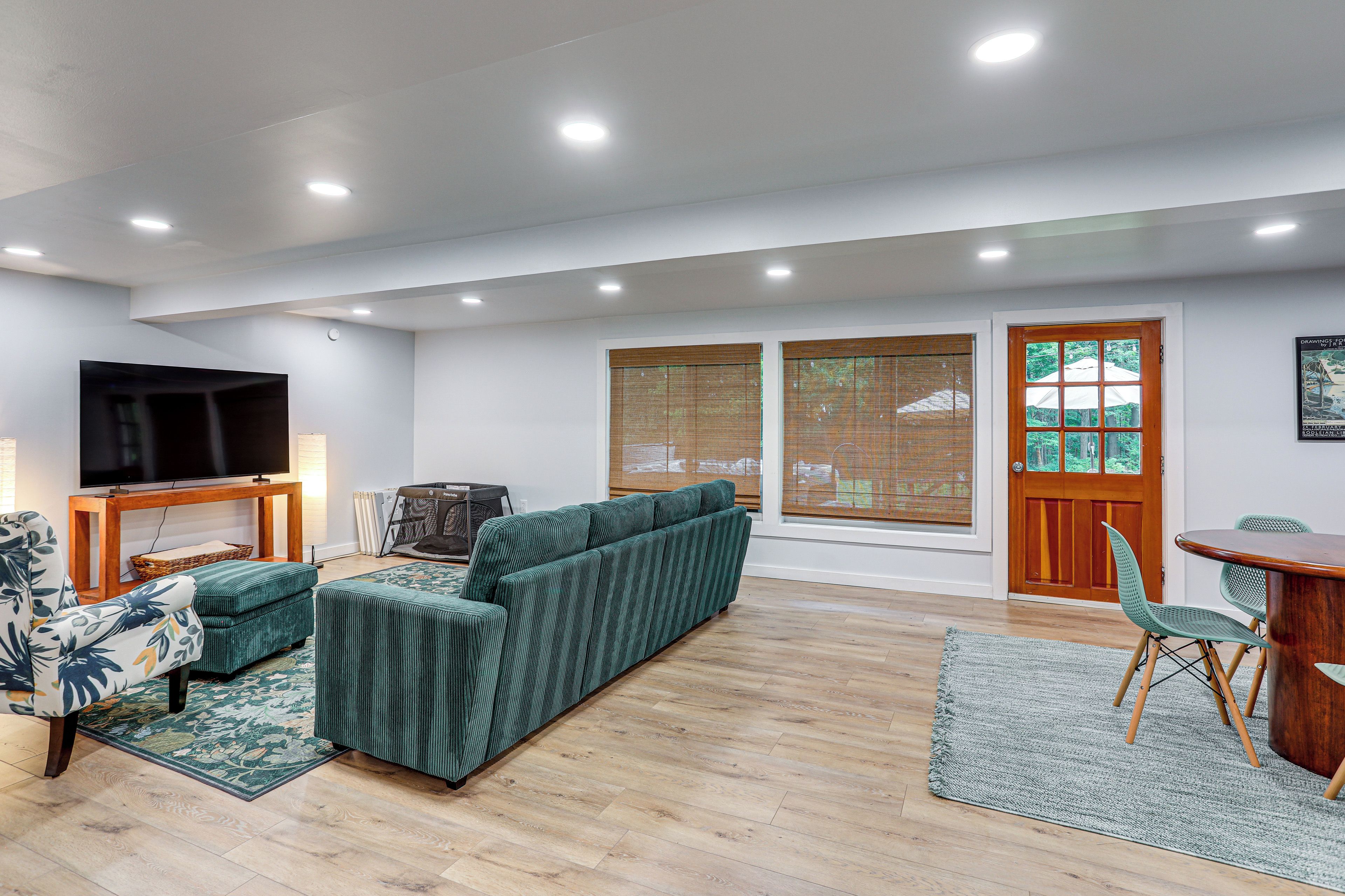A modern living room with a sectional sofa, a flat-screen TV, and a dining area with a table and chairs.