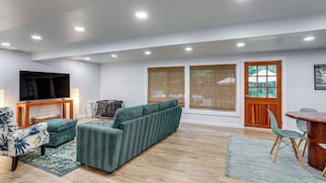 A modern living room with a sectional sofa, a flat-screen TV, and a dining area with a table and chairs.