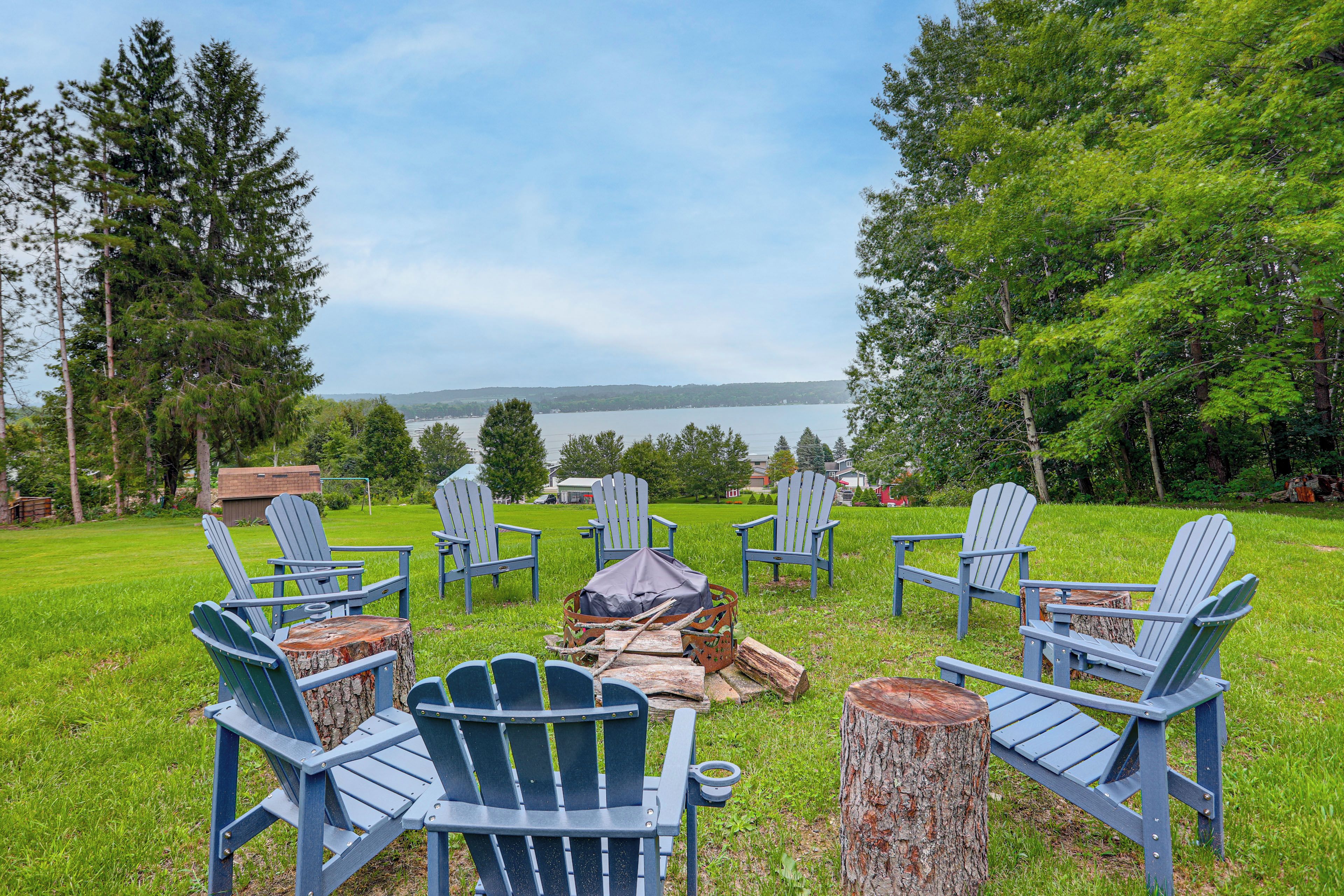 A lakeside seating area with Adirondack chairs and a fire pit.