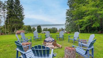 A lakeside seating area with Adirondack chairs and a fire pit.